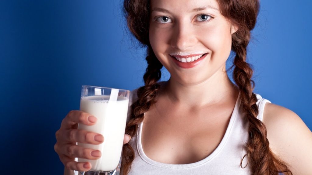 A woman is holding a glass of milk